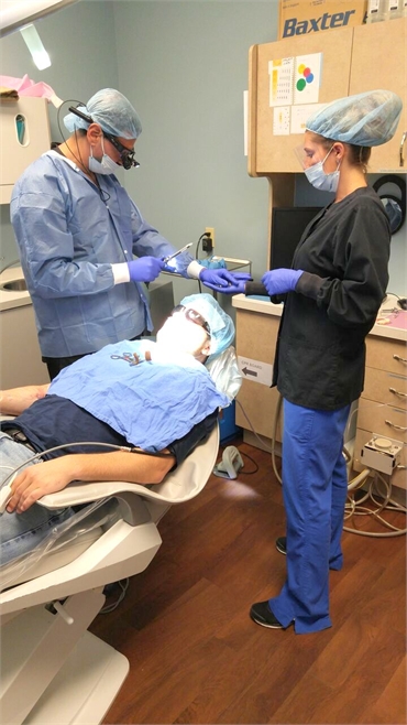 Dentist and dental hygienist performing dental implant procedure