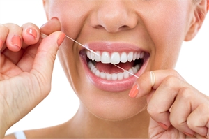 Beautiful woman flossing her healthy white teeth