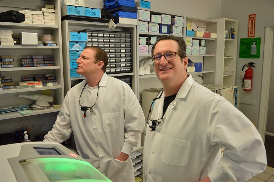 Elizabeth dentists Dr. Joseph and Jonathan Banker near CEREC crown milling machine at Banker Dental 