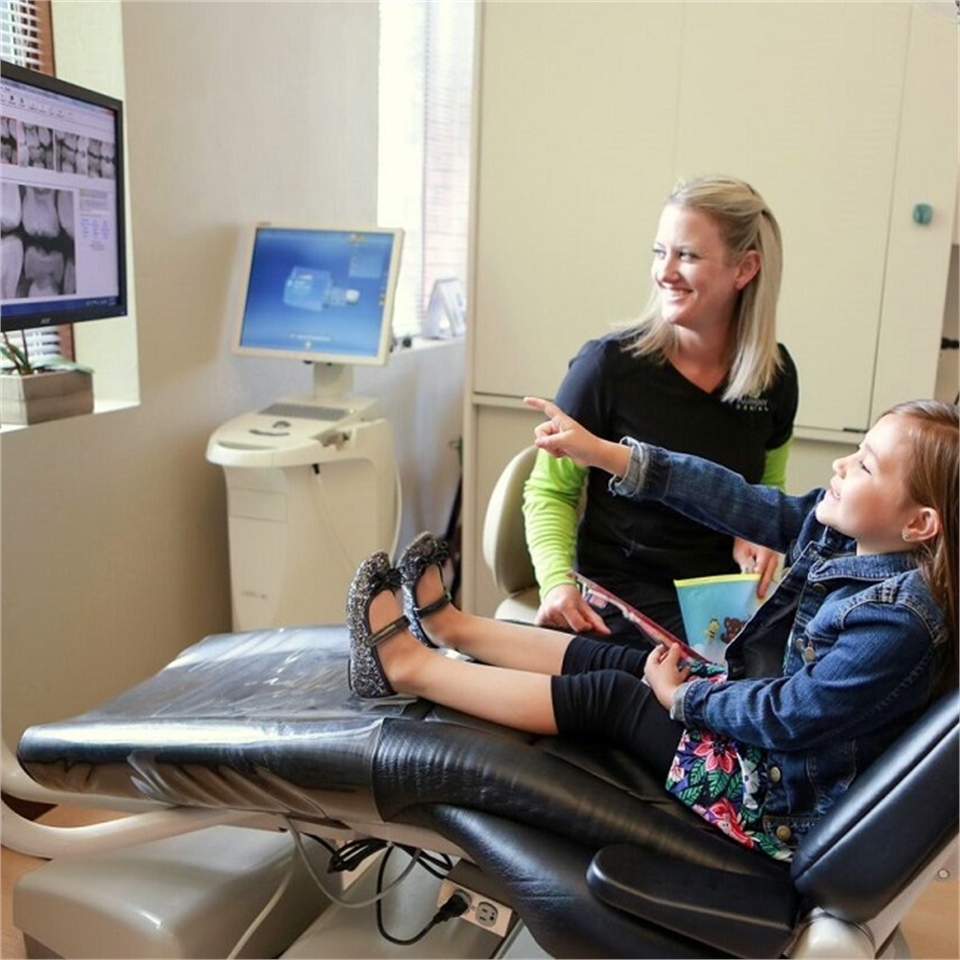 Dental Hygienist explains root canal therapy to child patient at Harmony Dental