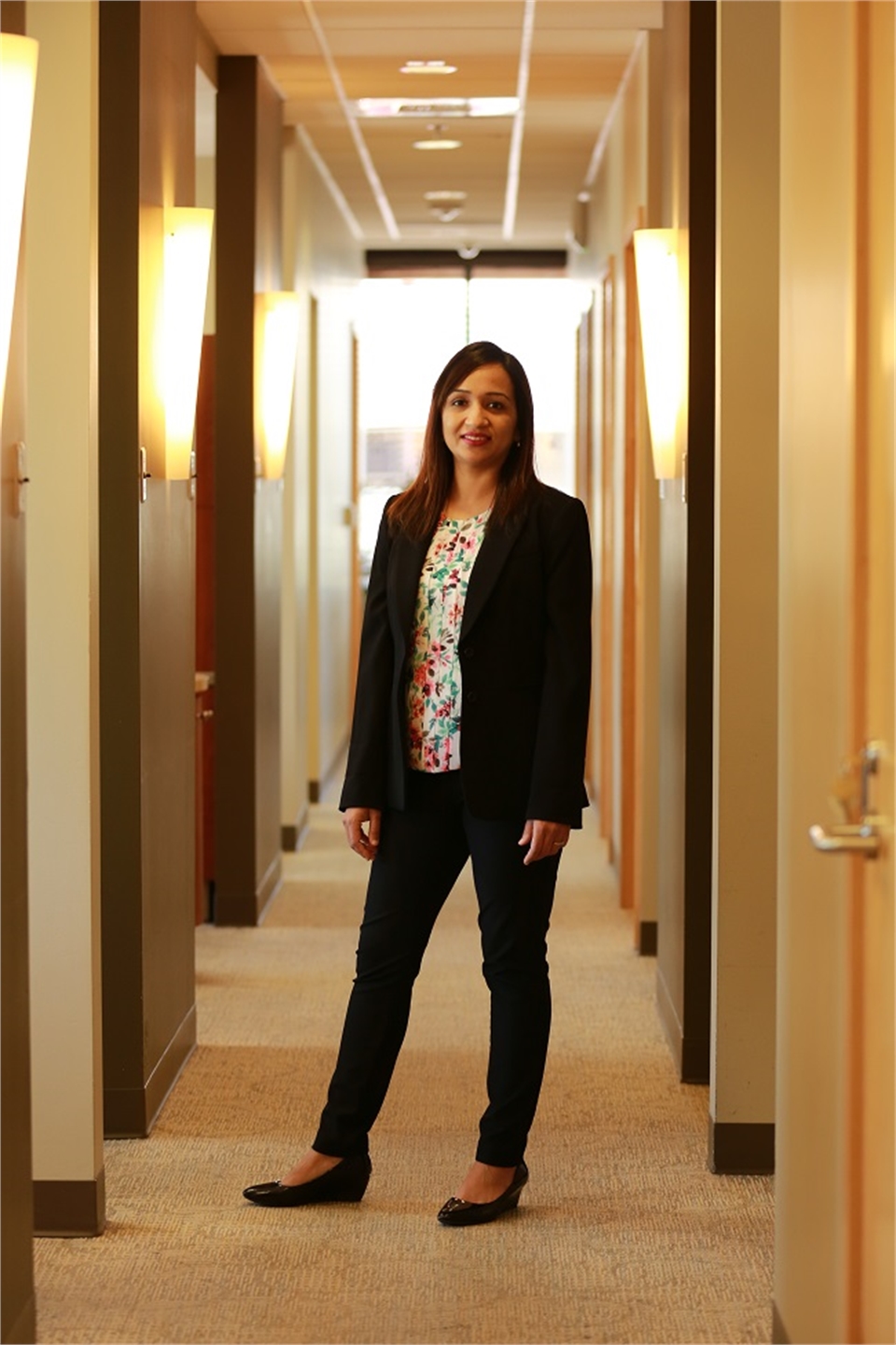 Renton dentist Dr. Pawandeep Kaur standing in the hallway at Renton Smile Dentistry