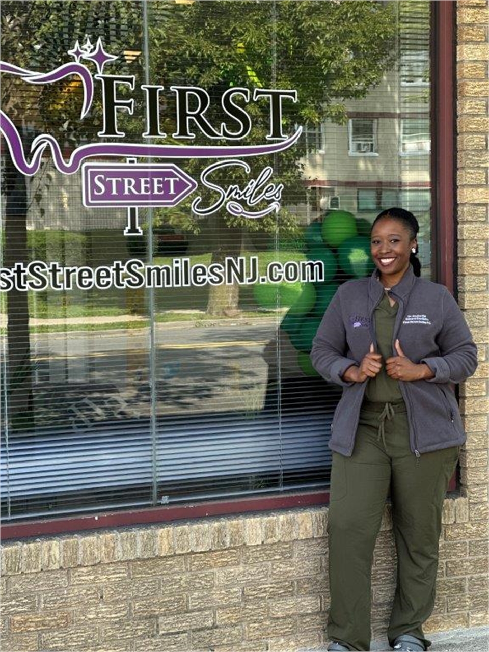 Hackensack pediatric dentist Dr. Nneka Obi outside her office with the First Street Smiles signage i