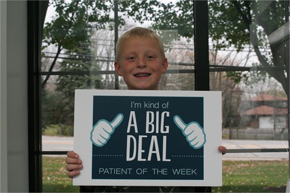 Young patient posing with sign at Gurnee IL dentist Bradley Rule DDS