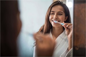 Woman brushing teeth at home