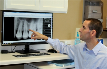 Dr. Brian Cook explaining root canal procedure using x-ray photos