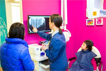 Pediatric dentist Dr. Ciano explaining the dental x-ray results to her patient's parent