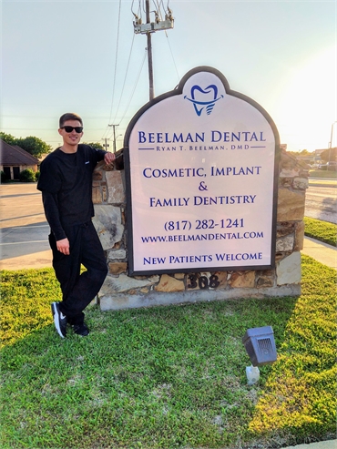 Bedford dentist Dr. Ryan Beelman standing near the signboard of Beelman Dental on Harwood Road