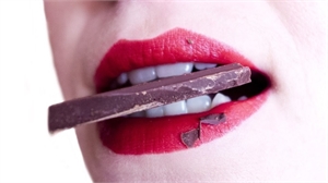 Woman with red lipstick eating chocolate