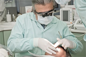 Dentist performing teeth checkup with magnifying loupes