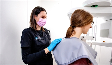 Dental hygienist assisting ClearBraces patient to the 3 D X-ray unit at Dentistry By The Bay Barrie 