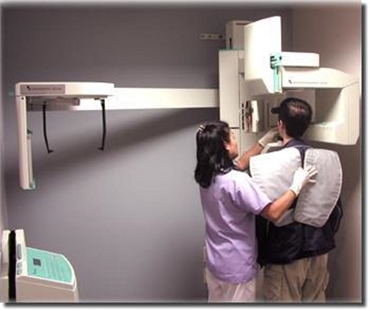 dental hygienist helps patient during x-ray procedure